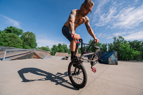 Wide angle view of an urban tattooed man doing tricks and stunts